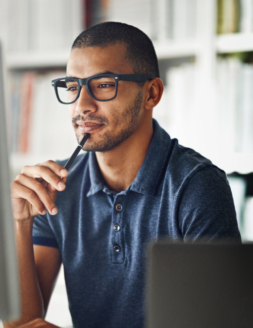 man wearing glasses thinking looking at monitor